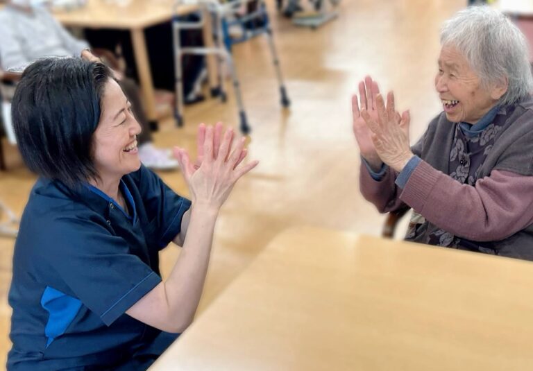 介護職員と入居者がハイタッチで交流するレクリエーション風景